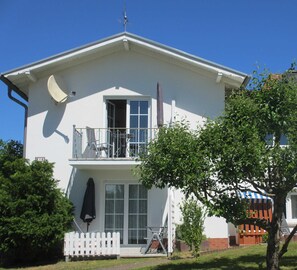 Un bâtiment à deux étages doté d’un balcon, d’une antenne parabolique et d’une clôture blanche en bois.