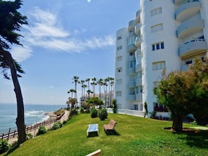 A hotel with a white exterior, multiple balconies, and a view of the ocean.