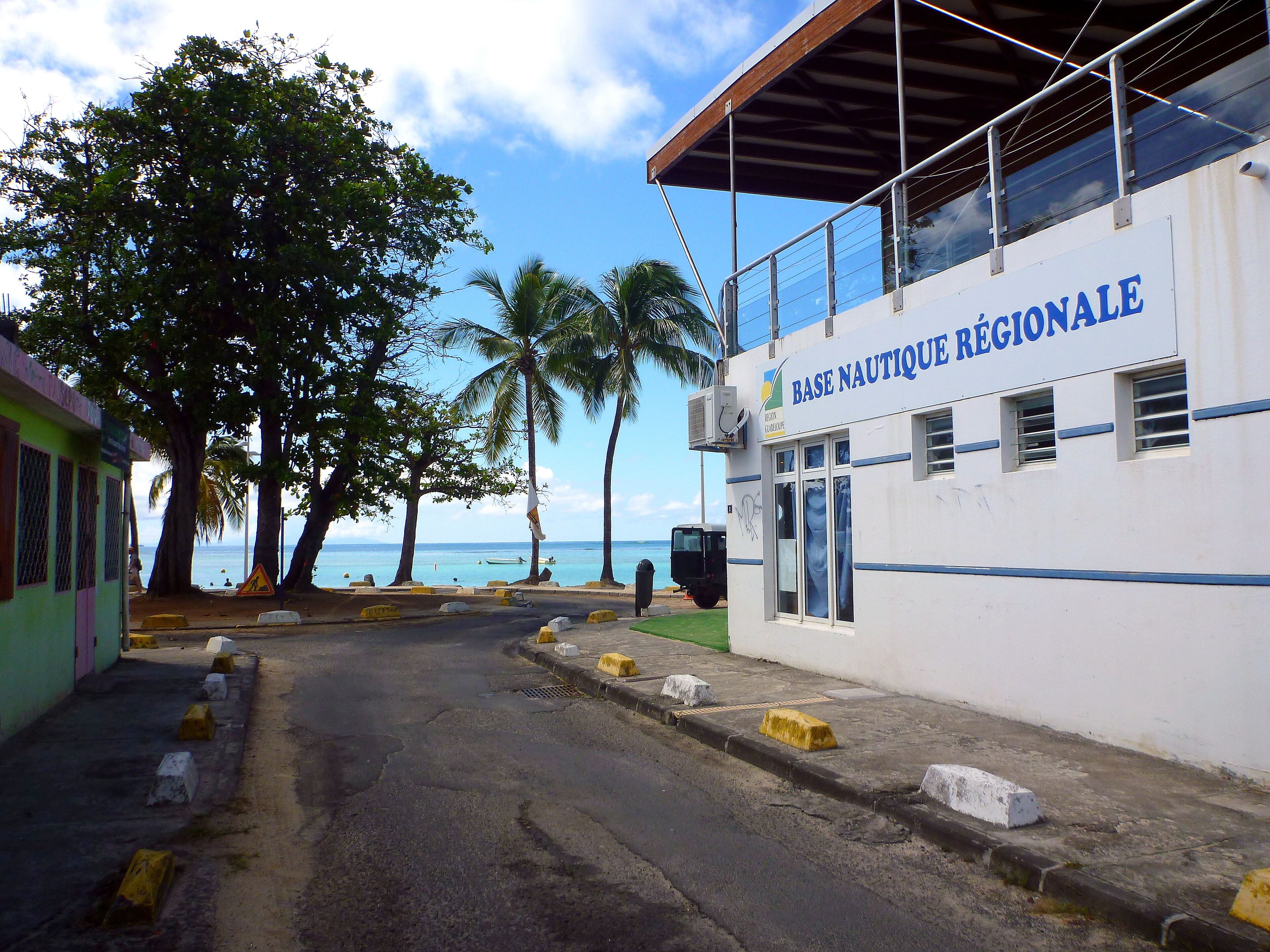 A building with a sign reading "BASE NAUTIQUE RÉGIONALE" and a view of the sea.