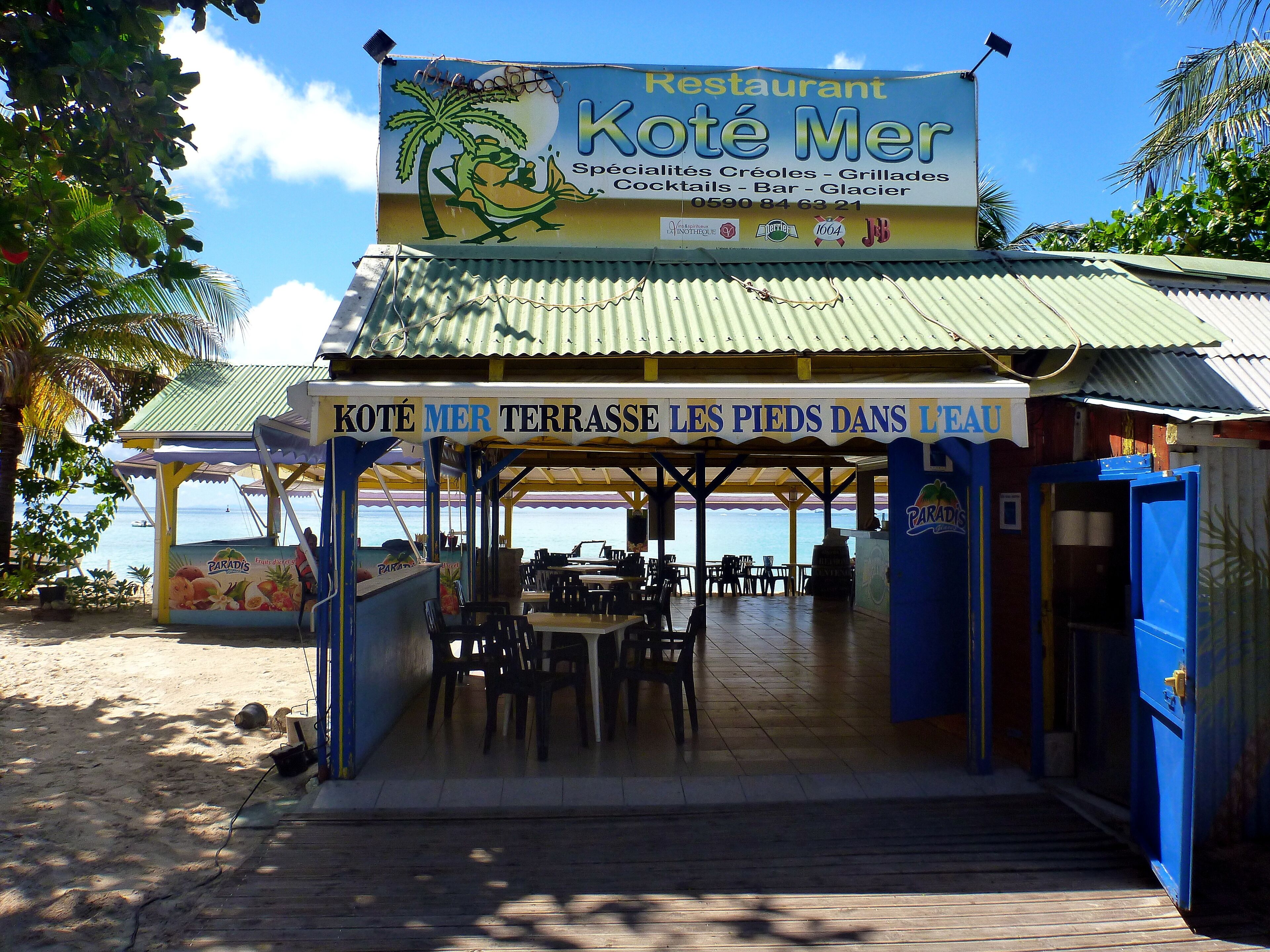 A beachside restaurant with outdoor seating and a view of the sea.