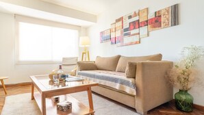 Un salon avec un canapé, une table basse, une lampe et des œuvres d’art accrochées au mur.