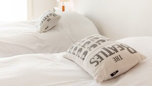 Une chambre d’hôtel avec un lit, deux oreillers, une table de chevet et une lampe.