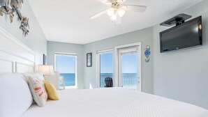 A bedroom with a large bed, a ceiling fan, a TV, and a view of the ocean through the windows. - Gulf Shores Beachfront Condo | Sleeps 6 | Gulf-Front Pool & On-Site Dining (Gulf Shores)