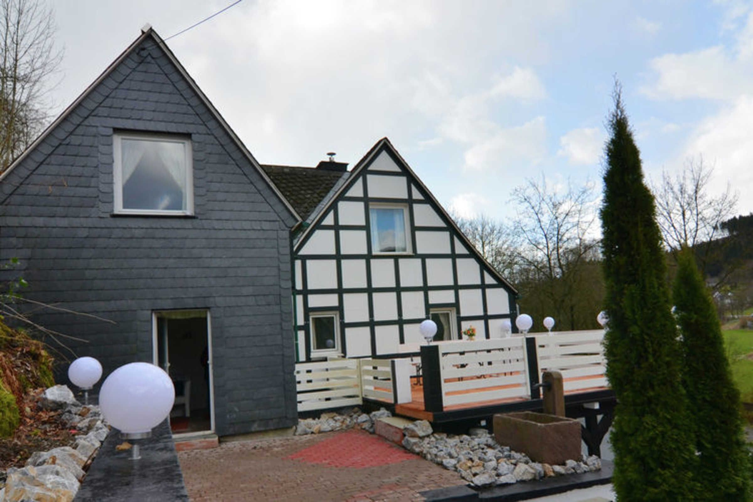 Une maison traditionnelle à colombages, avec une façade extérieure de couleur gris foncé et des éléments en bois peints en blanc.