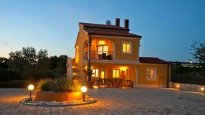 Une maison à deux étages avec un balcon, une allée et un jardin agrémenté de luminaires.