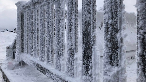Ein mit Schnee bedeckter Metallzaun mit vertikalen Streben.