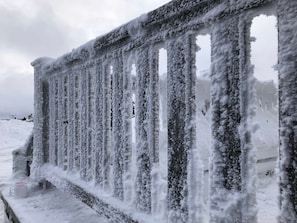 Ein mit Schnee bedeckter Metallzaun mit vertikalen Streben.