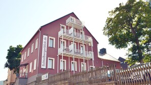 Ein mehrstöckiges Gebäude mit Balkonen, einer Steinsäule davor und einem Schild, das es als Hotel kennzeichnet.