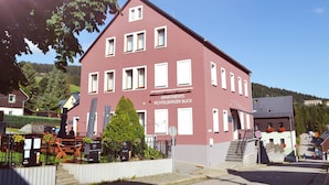 Ein mehrstöckiges Gebäude mit roter Fassade, zahlreichen Fenstern und einem Schild, das es als Mehrfamilienhaus kennzeichnet.