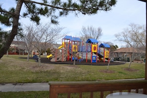 Ein Spielplatz mit Klettergerüsten und Rutschen, umgeben von Bäumen und einem Picknicktisch.