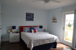 Una camera da letto con un letto, comodini, una ventola a soffitto, una finestra e vista all'esterno.
