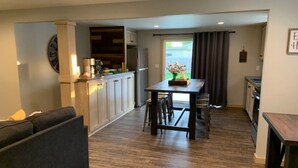 Une cuisine moderne avec des meubles en bois, une table à manger avec des chaises et un canapé dans l’espace salon.