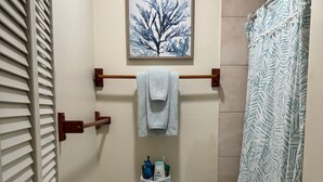 A bathroom with a toilet, a towel rack, a framed picture above the toilet, and a shower curtain. - 1 Bdrm Ocean View walk to Turtle Beach, close to Kona Village&Magic Sands Beach (Kailua)