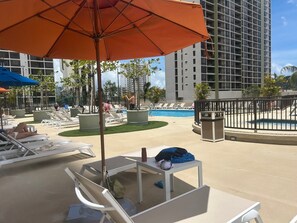 A poolside area with lounge chairs, umbrellas, and a pool.