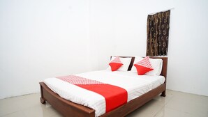 A neatly made bed with a wooden frame, white bedding, and red accents.