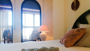 A hotel room with a bed, a lamp, a chair, and a view through an arched doorway. - A13 CONSULADO A 5º 3 (Calpe)