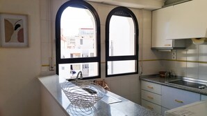 A kitchen with two arched windows, a stainless steel sink, and a granite countertop. - A13 CONSULADO A 5º 3 (Calpe)