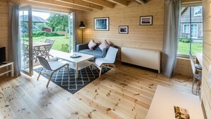 Un interior acogedor de madera con sofá, mesa de comedor y sillas, una chimenea y vistas al exterior.