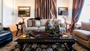 A living room with a sofa, a coffee table, and a lamp. - In town Villas- Suite 1 (2 Bedrooms) | Walk to Everything (Fredericksburg)