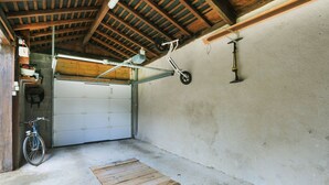 Un garaje con una bicicleta, una rampa de madera y una puerta de garaje blanca.