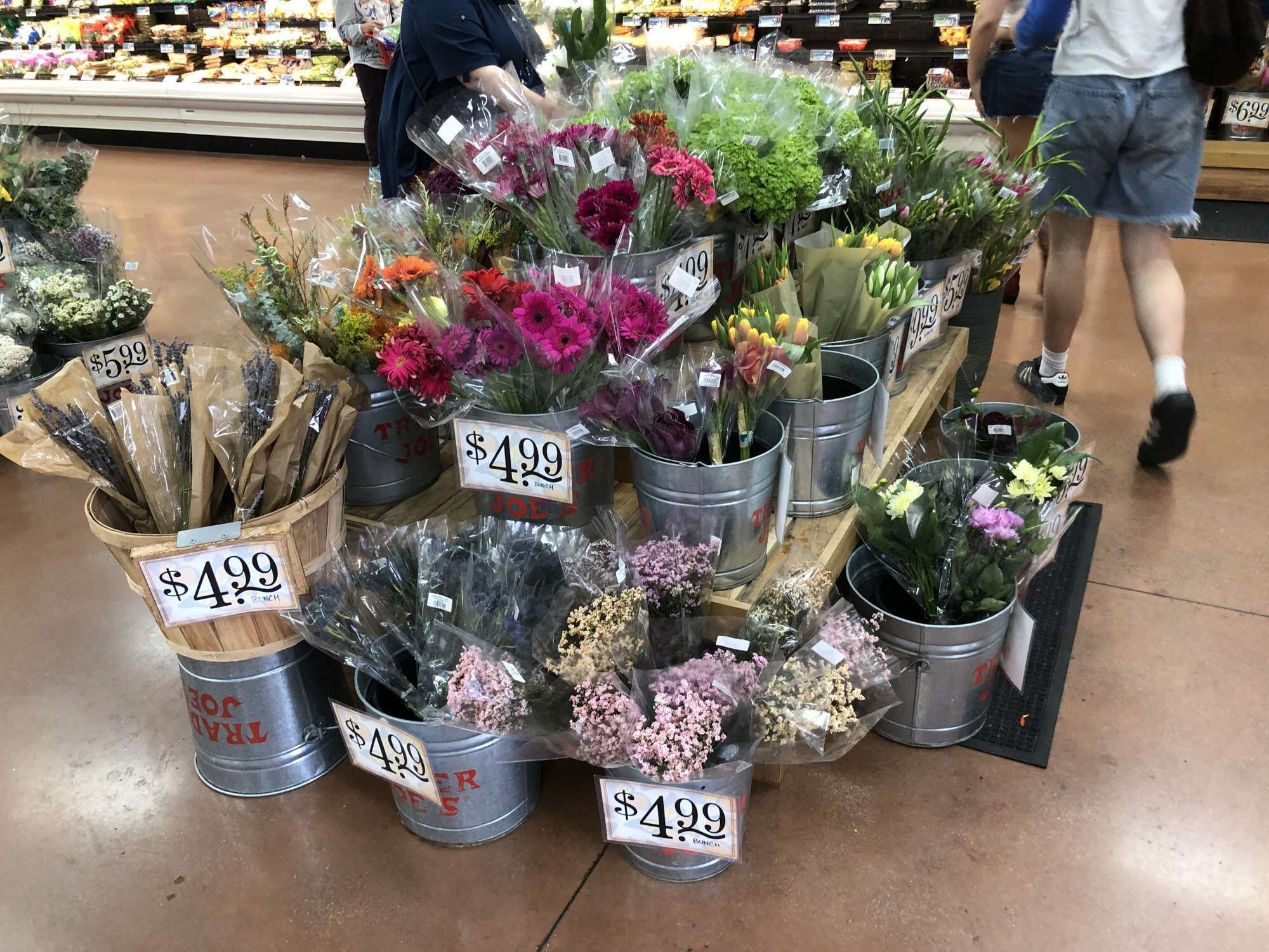 A flower display in a store with various types of flowers priced at $4.99.