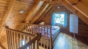A wooden attic bedroom with a bunk bed, a window with curtains, and a white wardrobe. - House 5 - SCHMIDT'S Cottages in the countryside (Lüdershagen)