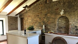 A kitchen with a stone wall, a brick oven, and a tiled floor.