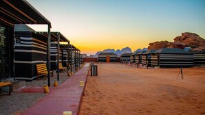 Un hotel en el desierto con carpas a rayas y un pasillo rojo.