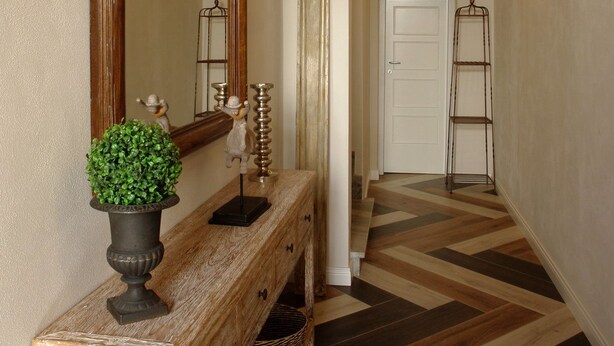 A hallway with a wooden console table, a large mirror, a potted plant, and a metal ladder against the wall. - Piazza Duomo Deluxe (Cecina)