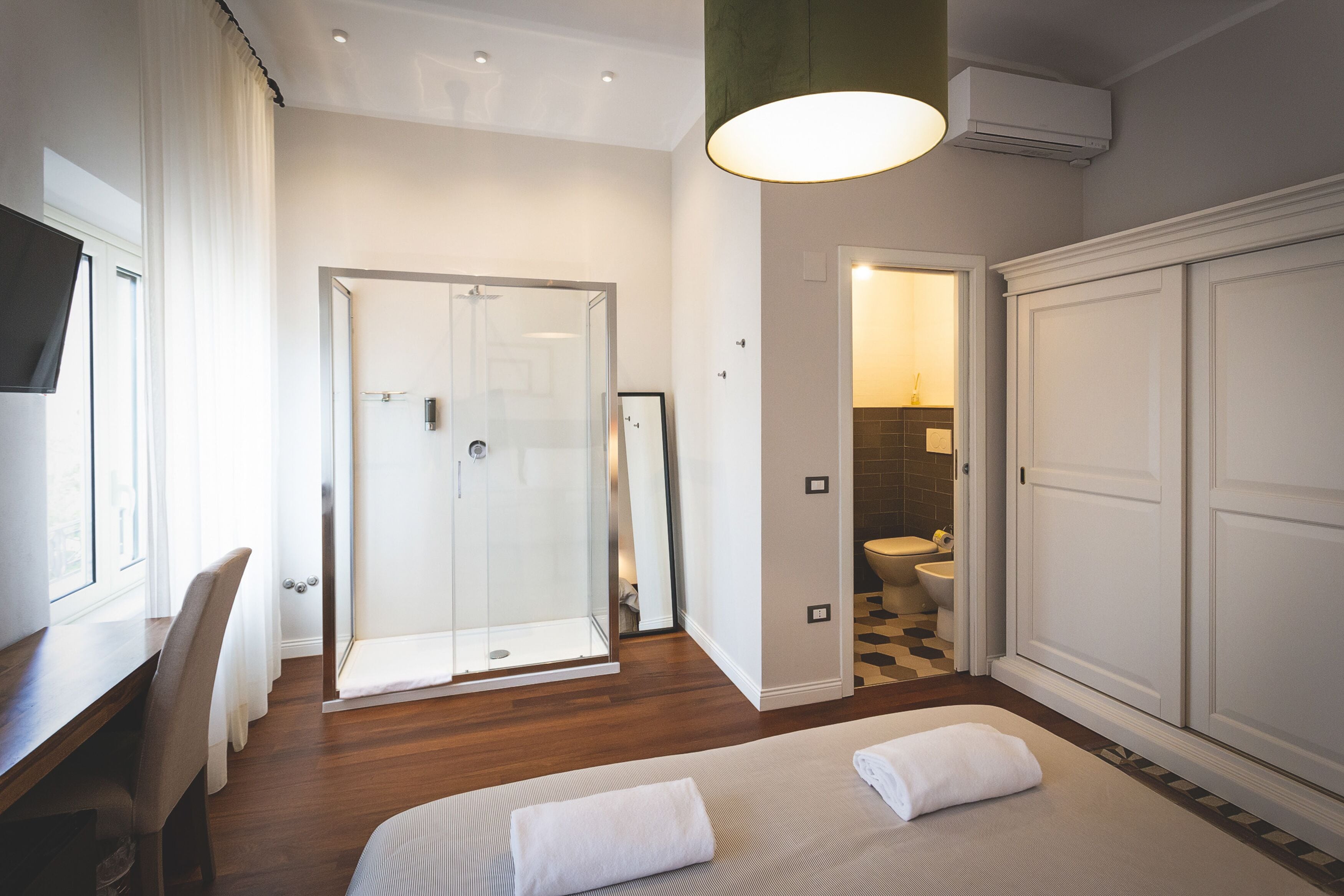Ein modernes Hotelzimmer mit Bett, Schreibtisch, Dusche und Badezimmer.