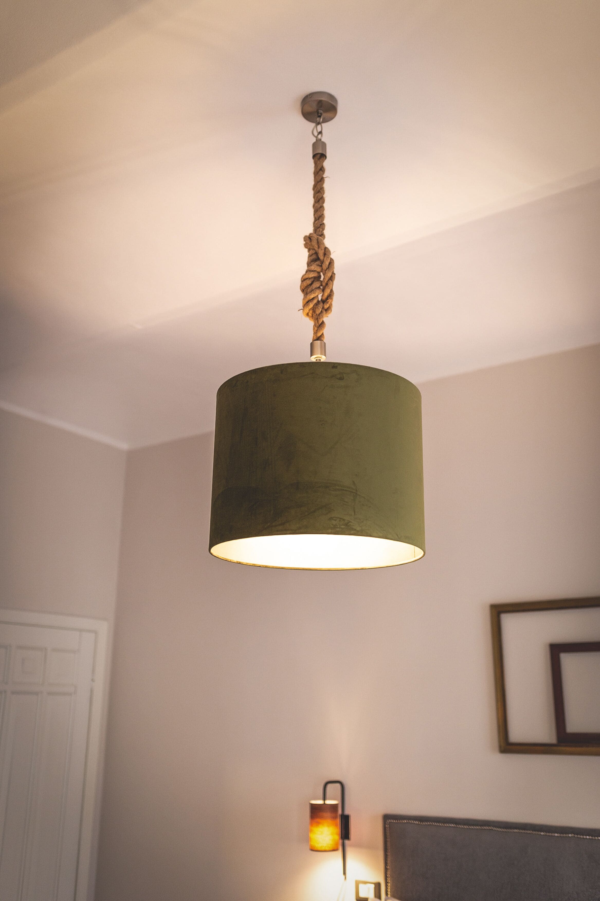 Une pièce avec un luminaire suspendu en forme de corde et une lampe fixée au mur.