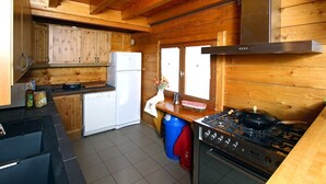 A compact kitchen with wooden cabinetry, a white refrigerator, a stove, and a sink.