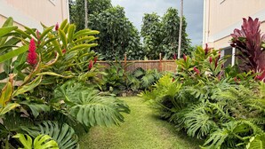 Um jardim bem cuidado, com diversas plantas tropicais e um gramado aparado.