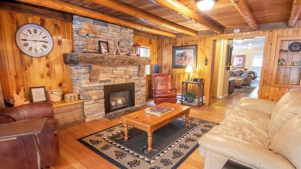 A cozy log cabin interior with a stone fireplace, leather furniture, and a rustic wooden ceiling. - Epic McCall Group Cabin | Close to Park, Lake,Town (McCall)