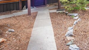 A log cabin with a stone chimney, a dark blue door, and a covered porch. - Epic McCall Group Cabin | Close to Park, Lake,Town (McCall)