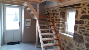 A staircase leading to a loft bedroom with stone walls and a window.