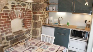 A compact kitchen with a stone wall, a built-in oven, a microwave, and a sink.
