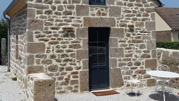 A stone building with a black door and a small window.