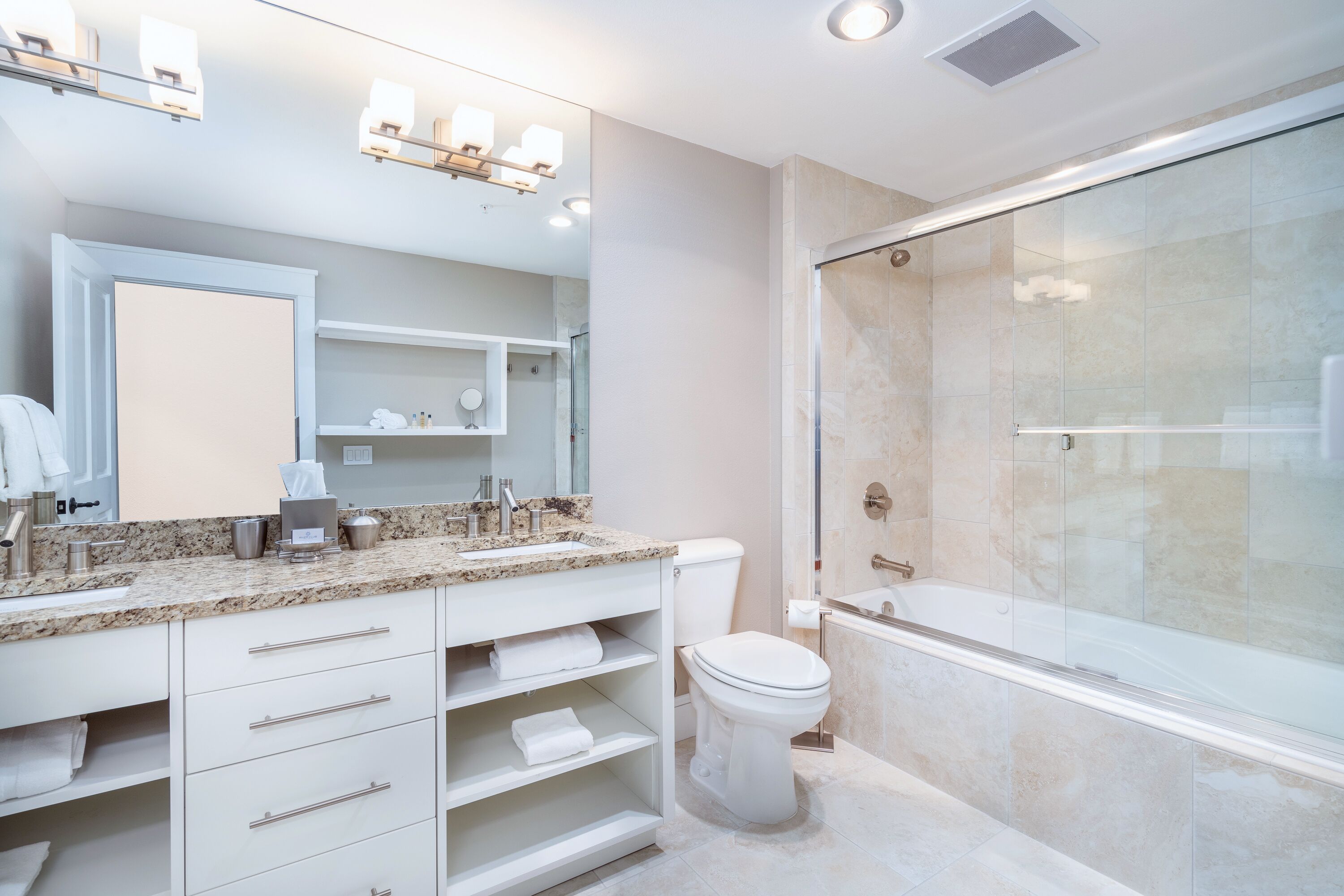 Een moderne badkamer met een douchecabine van glas, een wastafel met een marmeren blad en een toilet.