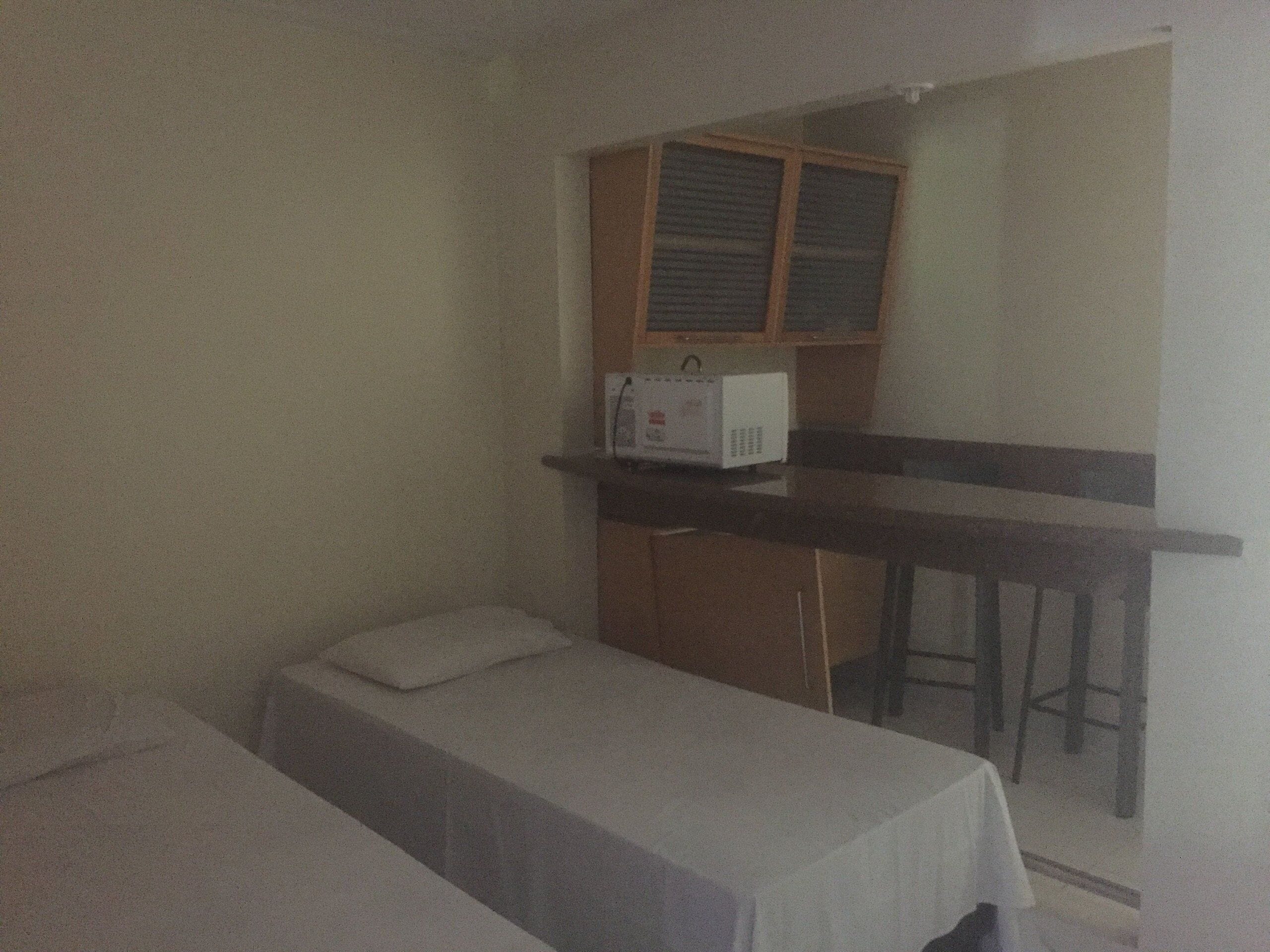 A small room with a single bed, a wooden cabinet, and a microwave on the counter.
