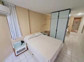 A hotel room with a bed, a bedside table, a wardrobe, and a bathroom door.