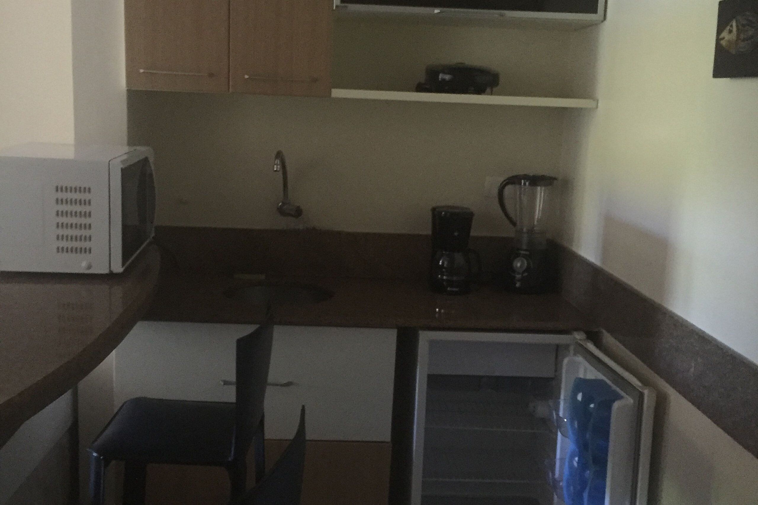 A compact kitchen with a microwave, a blender, and a refrigerator.