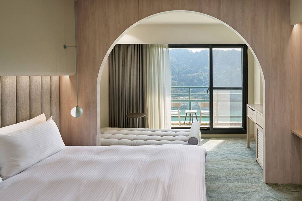 Ein Hotelzimmer mit Bett, Fernseher, Balkon mit Aussicht und Schreibtisch.
