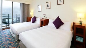 A hotel room with two beds, a balcony with a view, and a small table with a lamp. - Howard Lake Resort Shihmen Dam (Taoyuan City)