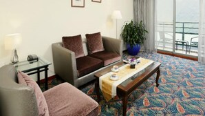 A hotel room with a sofa, armchair, coffee table, and a large window with a view. - Howard Lake Resort Shihmen Dam (Taoyuan City)