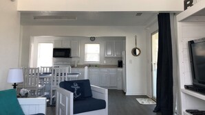 A compact living space with a kitchenette, a dining area, and a TV area. - Saltaire Cottage 11: 3BR Steps to Private Beach Access Screened Porch Pool (Kitty Hawk)