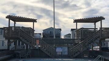 A swimming pool with wooden steps and a lifeguard warning sign.