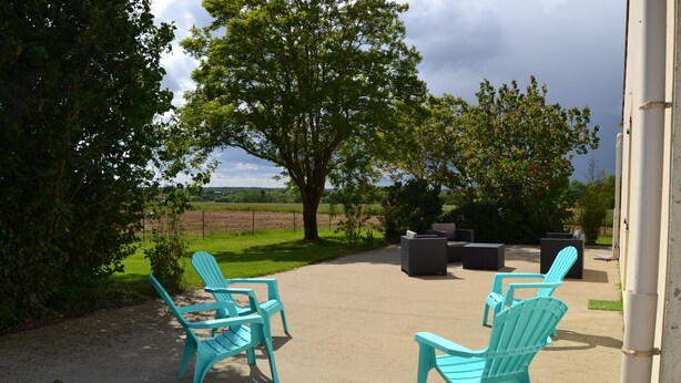 Eine Terrassengruppe im Freien mit türkisfarbenen Adirondack-Stühlen und einem Betonboden.