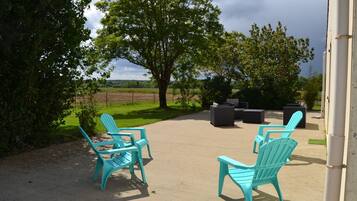 An outdoor patio with turquoise Adirondack chairs and a concrete floor.
