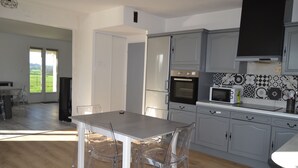 Eine moderne Küche mit grauen Schränken, einem eingebauten Backofen, einer Mikrowelle und einem Essbereich mit Tisch und Stühlen.
